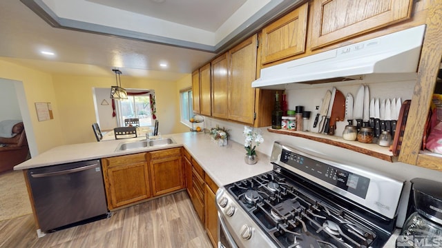 kitchen with sink, light wood-type flooring, kitchen peninsula, stainless steel appliances, and pendant lighting