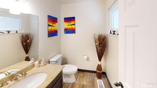 bathroom featuring a healthy amount of sunlight, vanity, hardwood / wood-style floors, and toilet