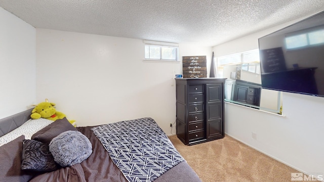 bedroom featuring a textured ceiling, multiple windows, and light colored carpet