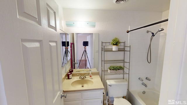 full bathroom with tiled shower / bath, vanity, and toilet