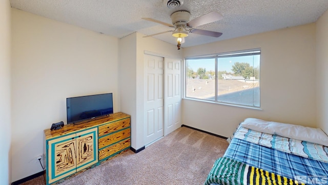 bedroom featuring a closet, a textured ceiling, carpet, and ceiling fan