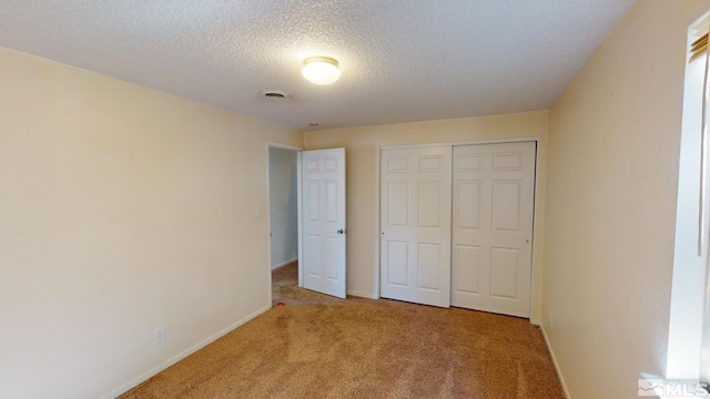 unfurnished bedroom with a closet, a textured ceiling, and light colored carpet