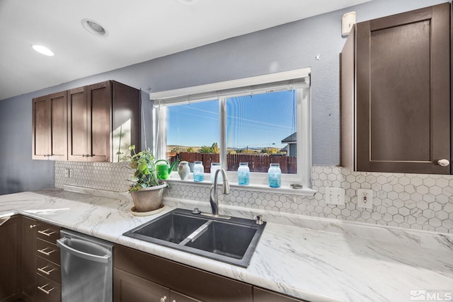 kitchen with light stone countertops, dark brown cabinetry, tasteful backsplash, and sink