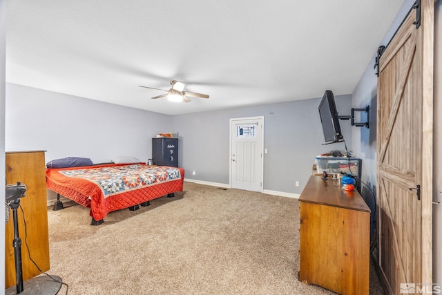 bedroom featuring a barn door, carpet floors, and ceiling fan