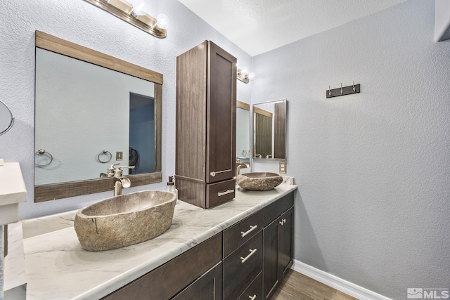 bathroom featuring hardwood / wood-style flooring, vanity, and a textured ceiling