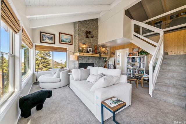 carpeted living room with wood ceiling, a stone fireplace, beamed ceiling, high vaulted ceiling, and wood walls