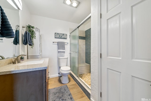 bathroom with vanity, toilet, a shower with shower door, and hardwood / wood-style floors