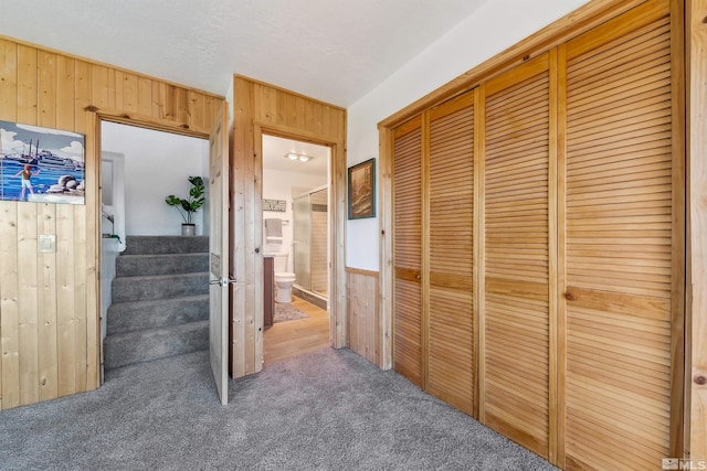 corridor featuring carpet floors and wooden walls