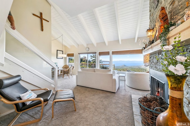 living room featuring high vaulted ceiling, a mountain view, light colored carpet, and a large fireplace