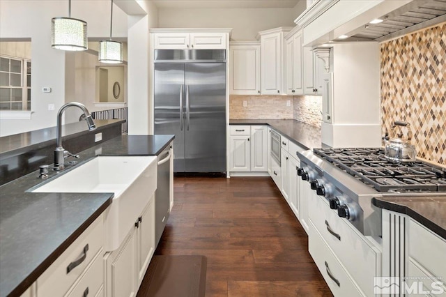 kitchen with custom exhaust hood, tasteful backsplash, dark hardwood / wood-style flooring, built in appliances, and decorative light fixtures