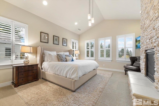 bedroom featuring light carpet, a stone fireplace, and high vaulted ceiling