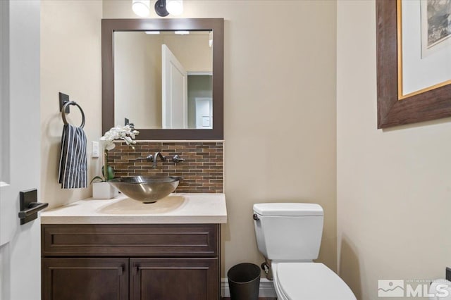 bathroom featuring vanity, toilet, and tasteful backsplash