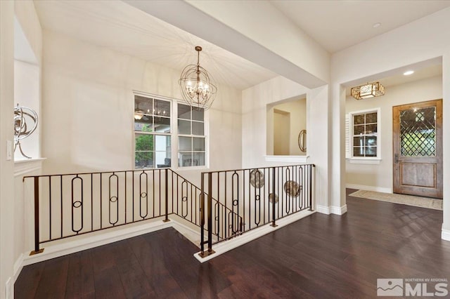 corridor with hardwood / wood-style flooring and an inviting chandelier