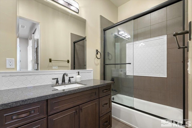 bathroom with vanity, tasteful backsplash, and shower / bath combination with glass door