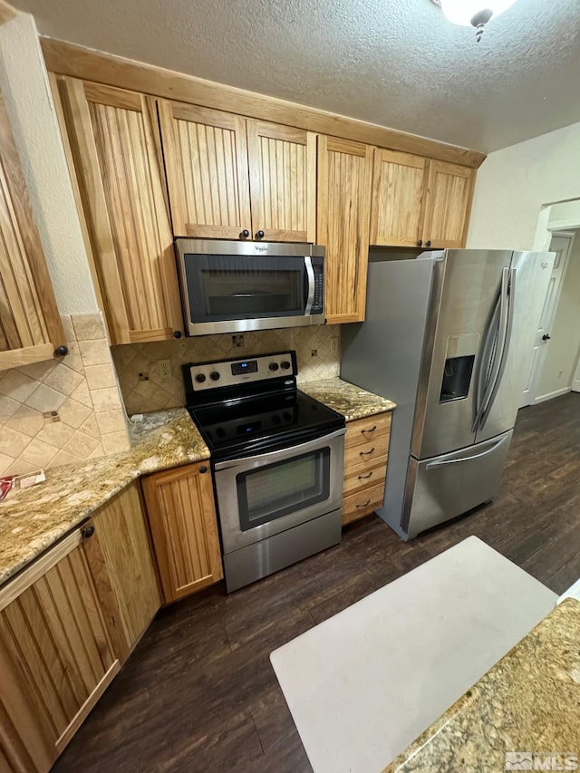 kitchen with tasteful backsplash, stainless steel appliances, dark wood-type flooring, and light stone counters