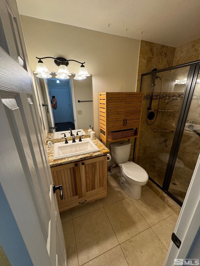 bathroom featuring vanity, toilet, tile patterned floors, and an enclosed shower