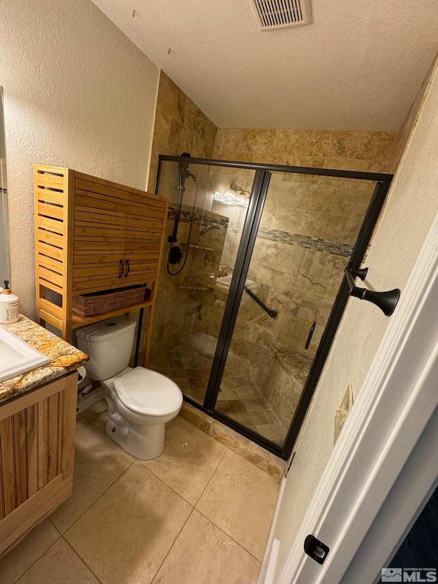 bathroom featuring vanity, a textured ceiling, toilet, and a shower with door