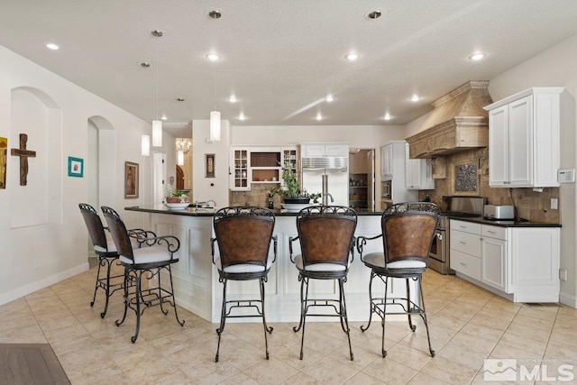 kitchen featuring appliances with stainless steel finishes, a kitchen island with sink, white cabinets, and tasteful backsplash