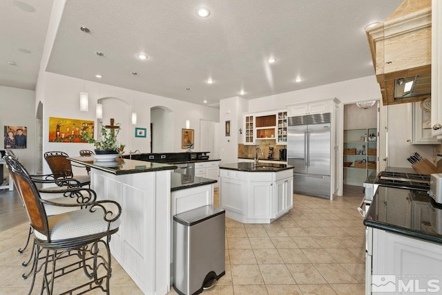 kitchen featuring a center island with sink, white cabinetry, sink, decorative light fixtures, and stainless steel appliances