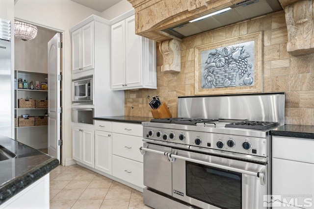 kitchen featuring white cabinetry, custom range hood, appliances with stainless steel finishes, and light tile patterned flooring