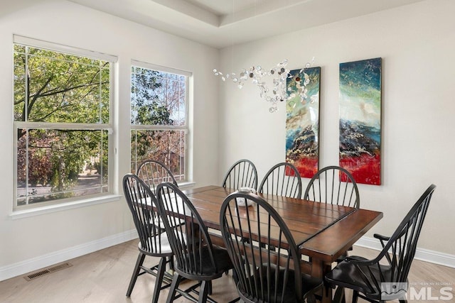 dining area with light hardwood / wood-style floors and a tray ceiling