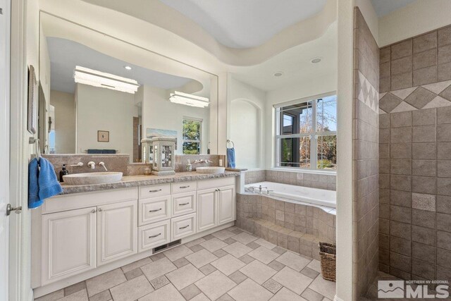 bathroom with vanity and tiled bath