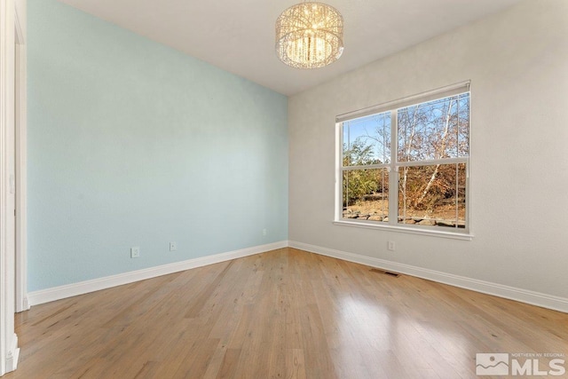 empty room with a notable chandelier and wood-type flooring