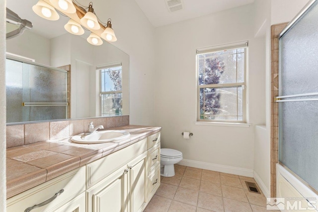 bathroom featuring vanity, toilet, a shower with shower door, and a wealth of natural light