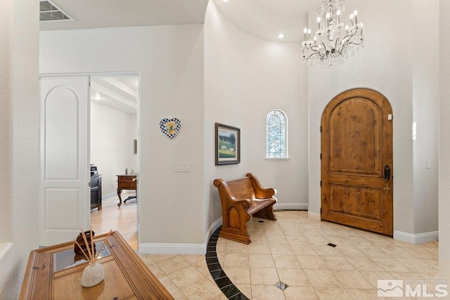 tiled entryway featuring a notable chandelier and a high ceiling