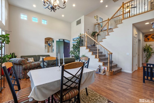 dining space with a high ceiling, light hardwood / wood-style flooring, and a chandelier