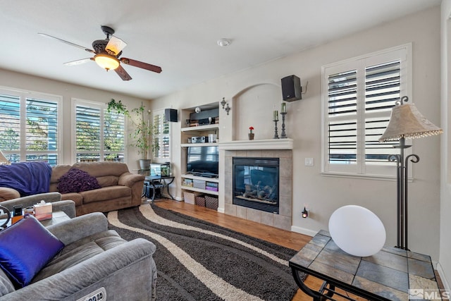 living room featuring ceiling fan, wood-type flooring, and a fireplace