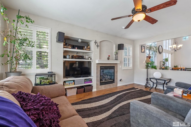 living room with a fireplace, wood-type flooring, and ceiling fan with notable chandelier