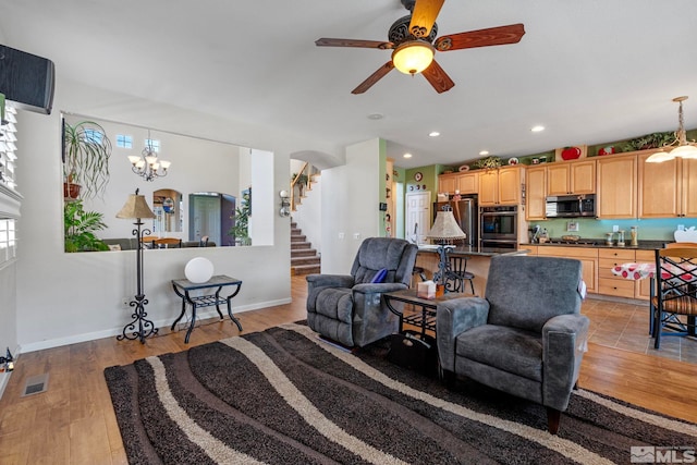 living room featuring light hardwood / wood-style floors and ceiling fan with notable chandelier