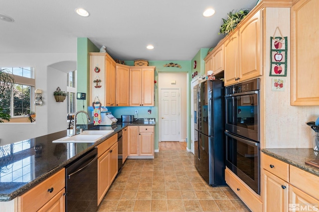 kitchen with light brown cabinetry, black appliances, sink, kitchen peninsula, and dark stone countertops