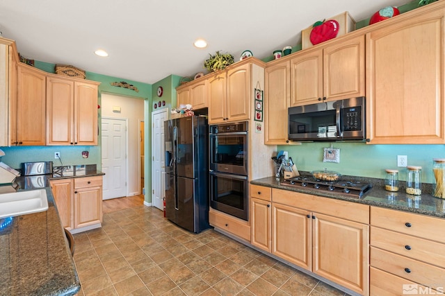 kitchen with dark stone countertops, appliances with stainless steel finishes, sink, and light brown cabinets