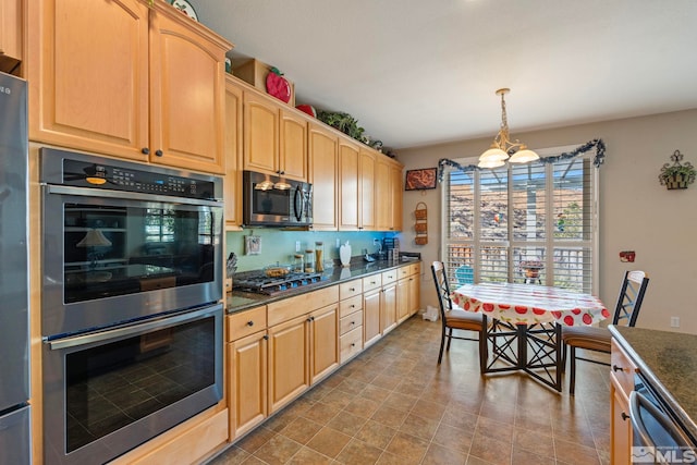 kitchen featuring hanging light fixtures, stainless steel appliances, dark stone counters, a notable chandelier, and light brown cabinetry