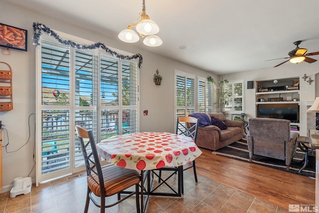 dining room with light hardwood / wood-style flooring and ceiling fan with notable chandelier