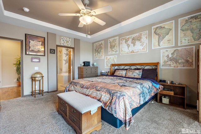 carpeted bedroom featuring connected bathroom, ceiling fan, and a raised ceiling