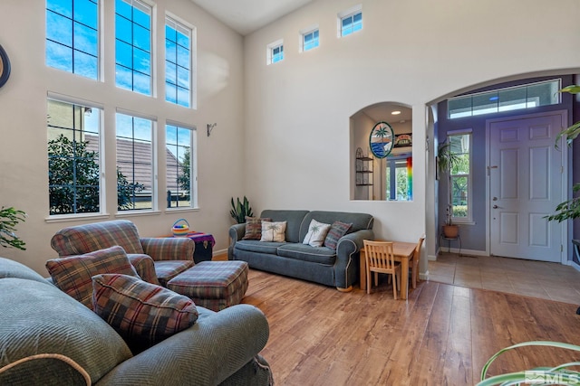 living room featuring a towering ceiling, light hardwood / wood-style flooring, and plenty of natural light