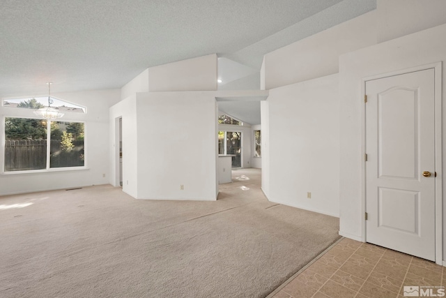 unfurnished room featuring lofted ceiling, a textured ceiling, a chandelier, and carpet flooring