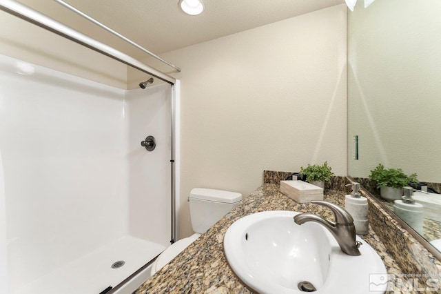 bathroom featuring toilet, a textured ceiling, sink, and a shower