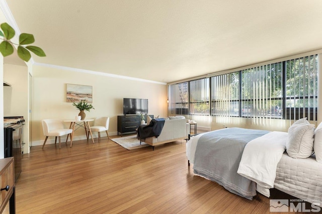 bedroom featuring light hardwood / wood-style floors, crown molding, and expansive windows