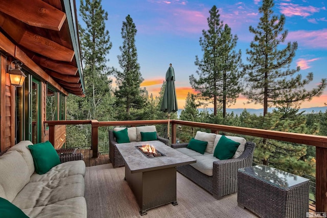 deck at dusk featuring an outdoor living space with a fire pit