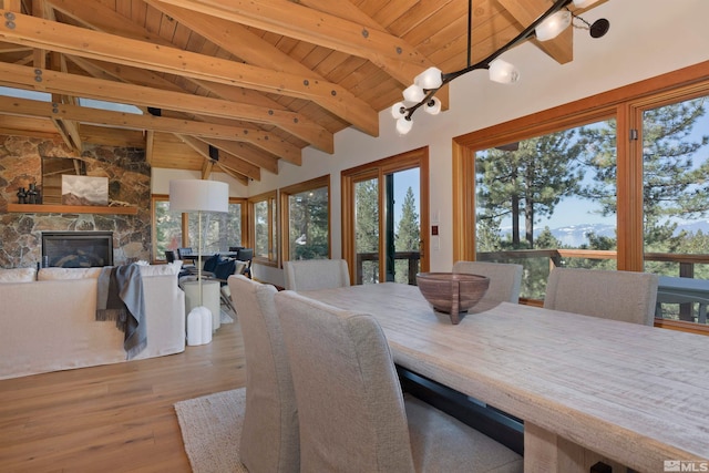 dining area with wood-type flooring, a fireplace, wood ceiling, beamed ceiling, and high vaulted ceiling