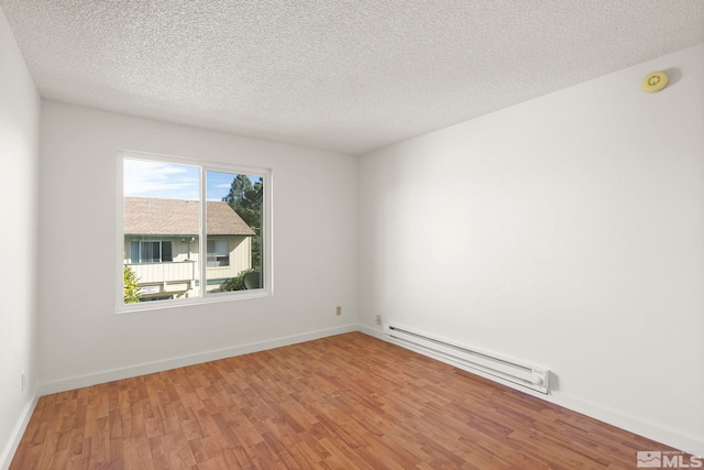 empty room featuring hardwood / wood-style floors, a textured ceiling, and a baseboard radiator