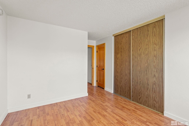 unfurnished bedroom with a textured ceiling, light wood-type flooring, and a closet