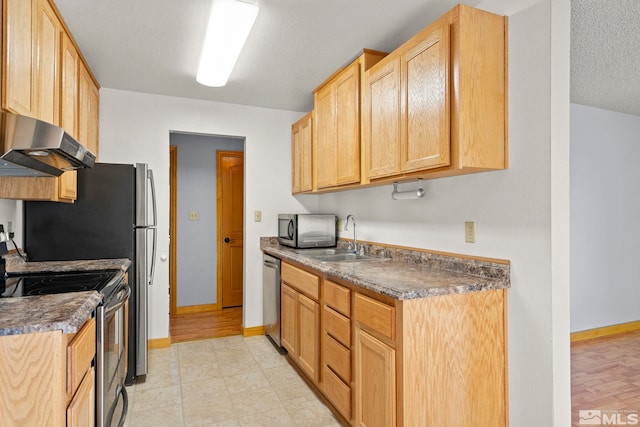 kitchen featuring exhaust hood, light hardwood / wood-style flooring, sink, appliances with stainless steel finishes, and a textured ceiling