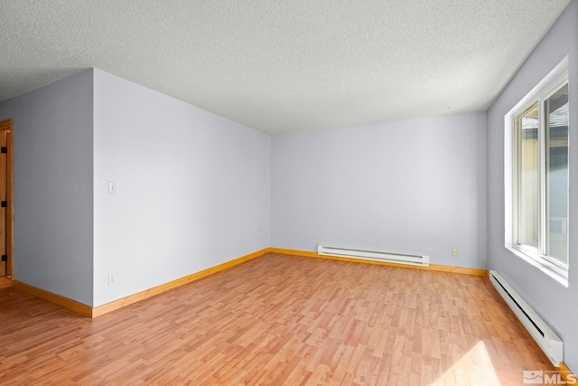 spare room with light hardwood / wood-style flooring, a baseboard radiator, and plenty of natural light