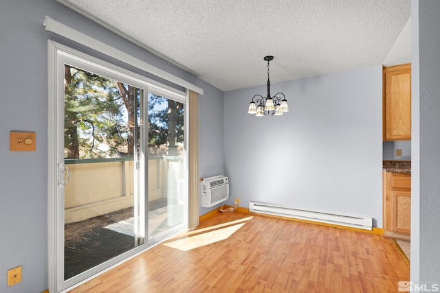 unfurnished dining area featuring baseboard heating, light hardwood / wood-style flooring, a wall mounted air conditioner, an inviting chandelier, and a textured ceiling