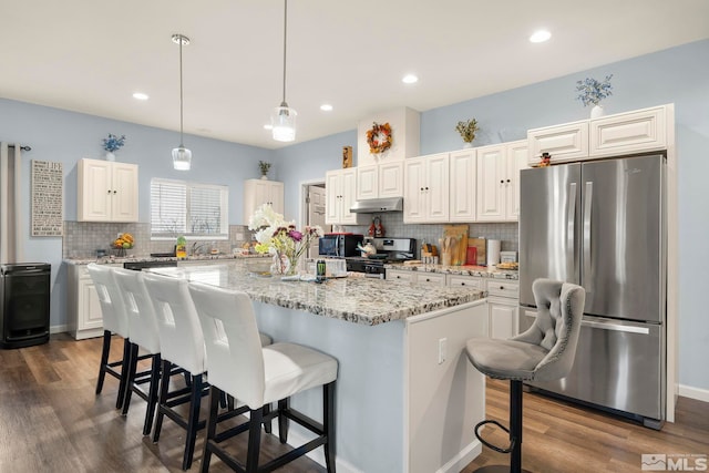 kitchen with hanging light fixtures, appliances with stainless steel finishes, white cabinetry, and a kitchen island